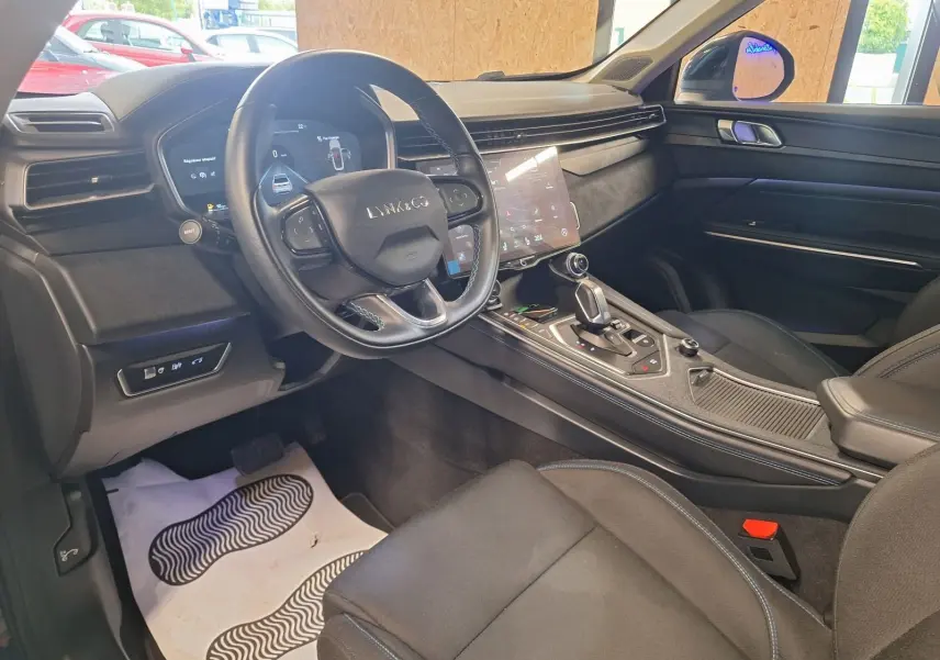 Vue intérieure côté conducteur du Lynk & Co 01 noir, avec volant multifonctions et écran tactile central lumineux.