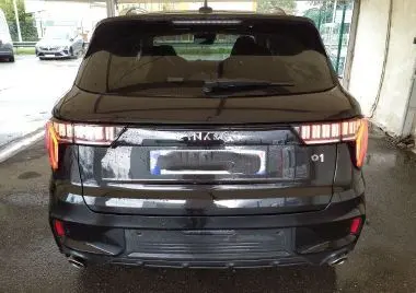 Vue avant d'un LYNK & CO 01 PHEV noir avec phares LED allumés dans un showroom intérieur.