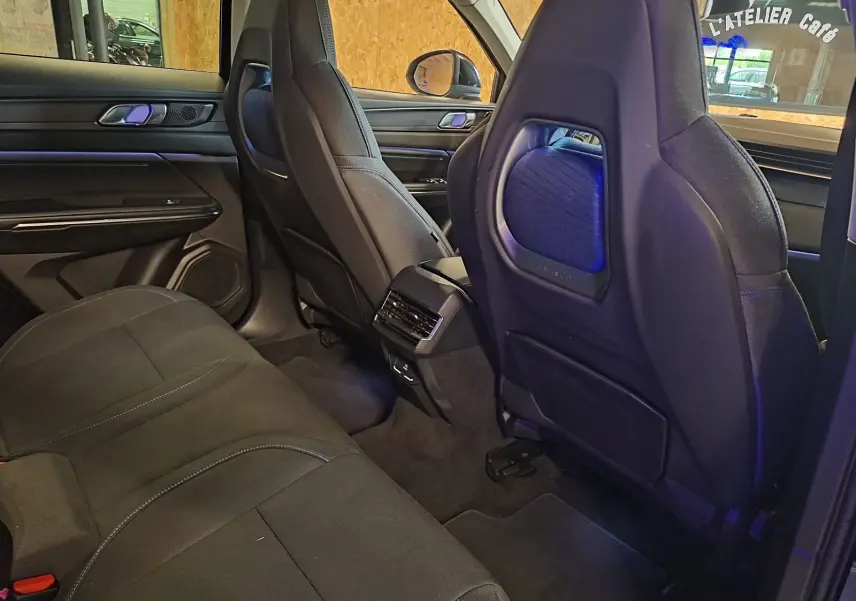 Vue intérieure arrière du Lynk & Co 01 noir, montrant les sièges avant avec éclairage d'ambiance bleu et banquette arrière.