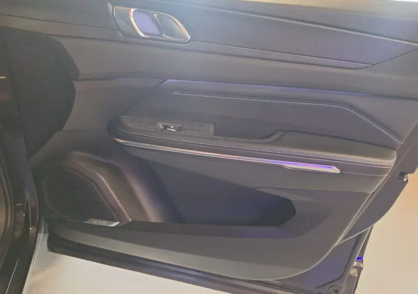 Vue intérieure du panneau de porte avant gauche noir du Lynk & Co 01 PHEV avec éclairage d'ambiance violet.