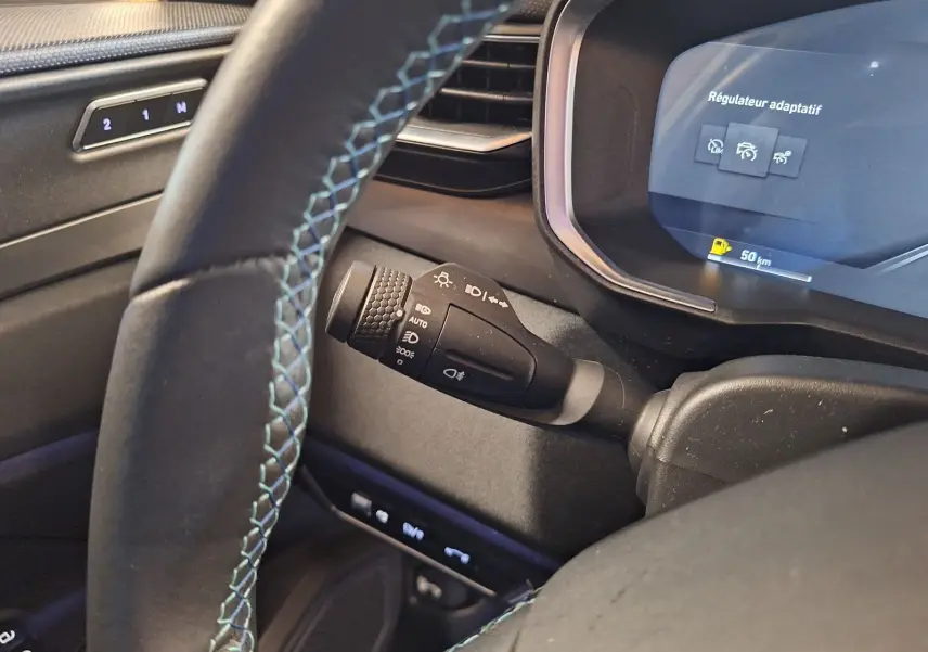 Vue rapprochée du volant et du combiné d'instruments du Lynk & Co 01 PHEV 2022, avec surpiqûres bleues et affichage du régulateur adaptatif.