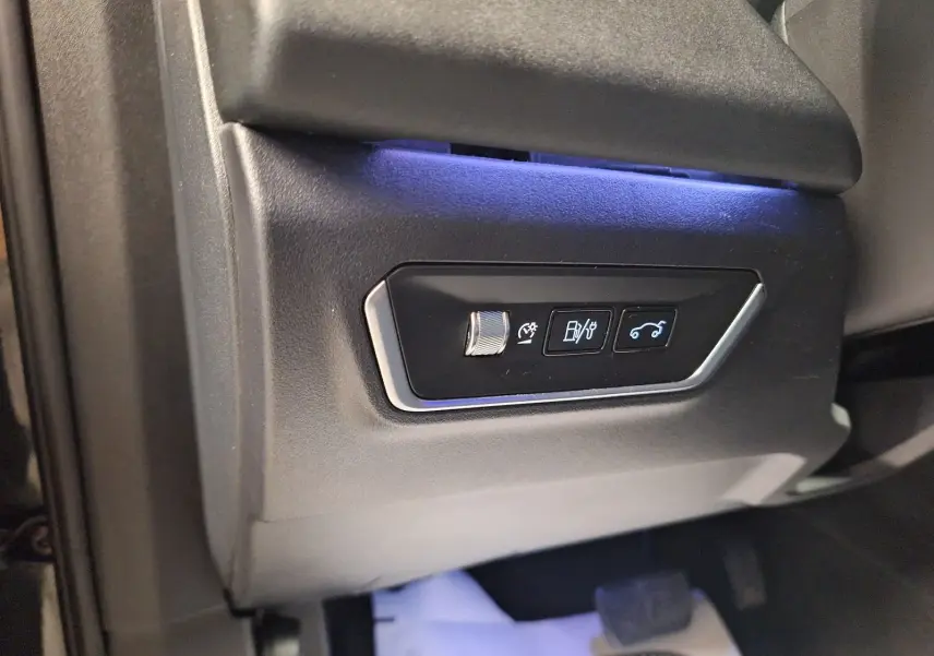 Détail des commandes d'ouverture du coffre et réglages, côté gauche intérieur d'un Lynk & Co 01 noir.