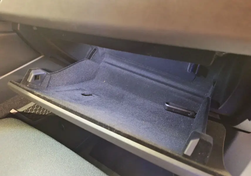 Gros plan sur la boîte à gants noire ouverte du Lynk & Co 01 PHEV 261 DCTH7, intérieur tissu sombre.