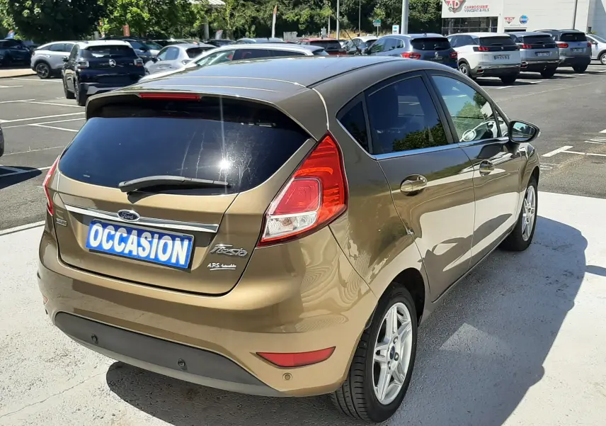 Vue 3/4 arrière droite d'une Ford Fiesta marron métal 5 portes, avec vitres teintées et jantes alliage argentées.
