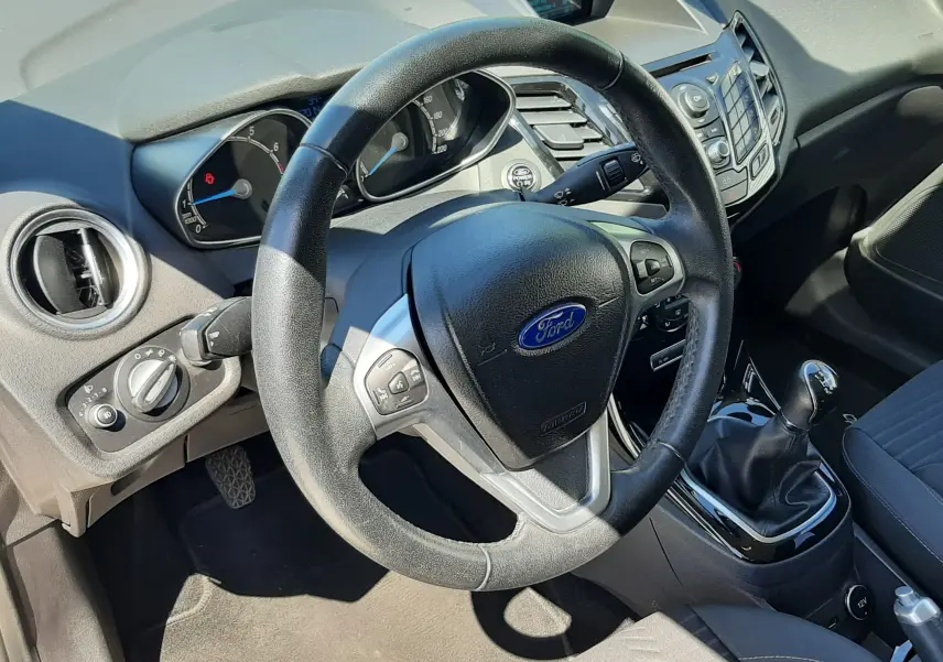 Intérieur noir de la Ford Fiesta 2013, vue côté conducteur sur le volant multifonction et la boîte manuelle.