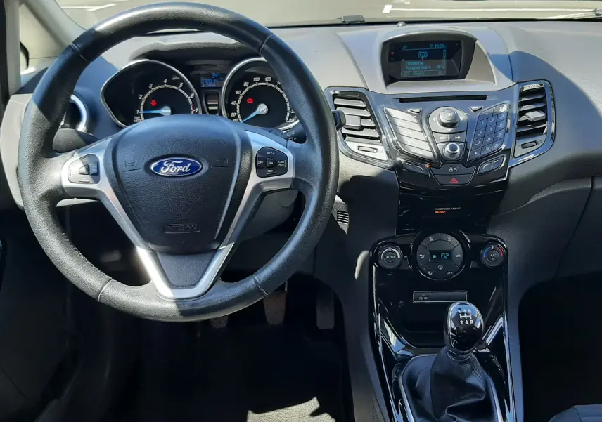 Vue intérieure avant centrée sur le volant multifonction et la console centrale brillante de la Ford Fiesta 2013.