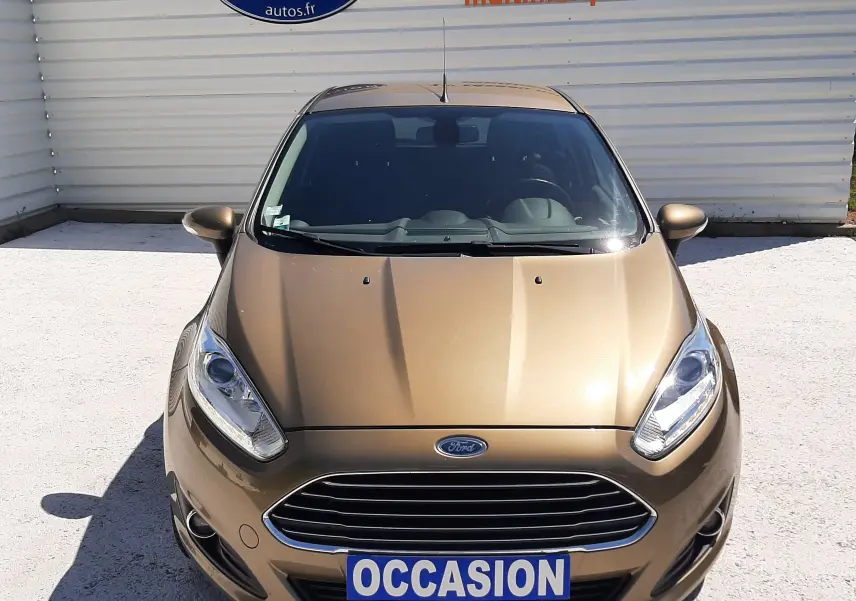 Vue avant d'une Ford Fiesta marron métal 2013 avec calandre chromée et plaque "OCCASION" visible.