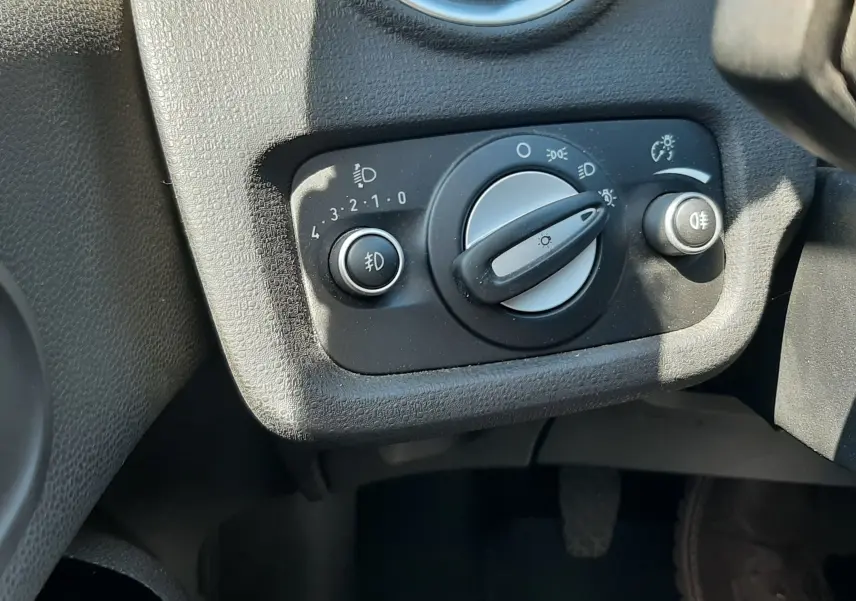Gros plan sur le panneau de commande des phares dans l'habitacle noir d'une Ford Fiesta marron métal de 2013.