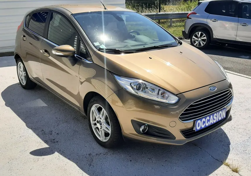 Ford Fiesta marron métal vue 3/4 avant droit, compacte 5 portes avec calandre chromée et jantes alliage.