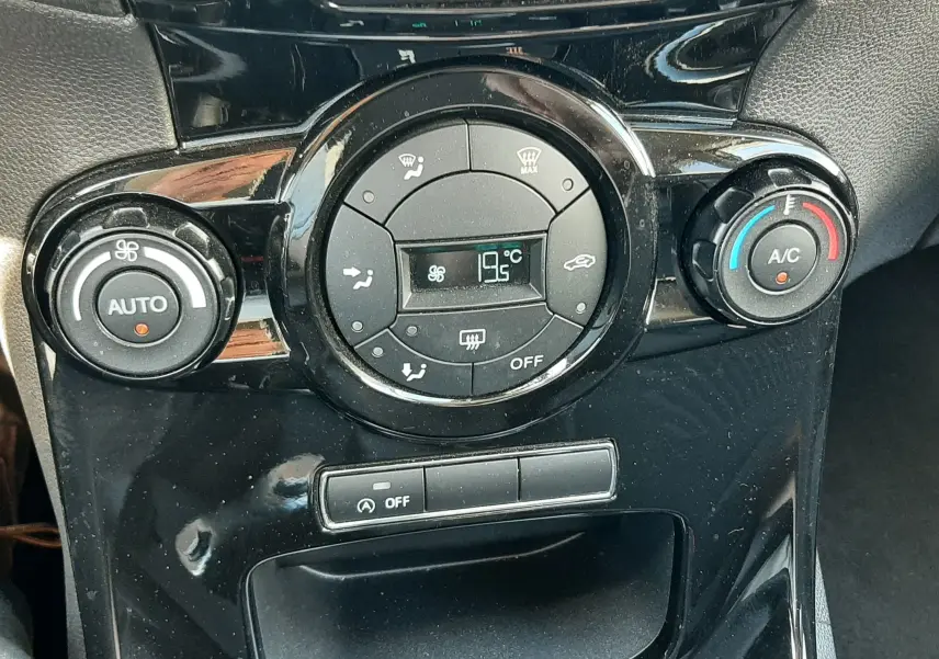 Vue rapprochée du tableau de bord de la Ford Fiesta marron métal, avec commande de climatisation et indicateur airbag passager.