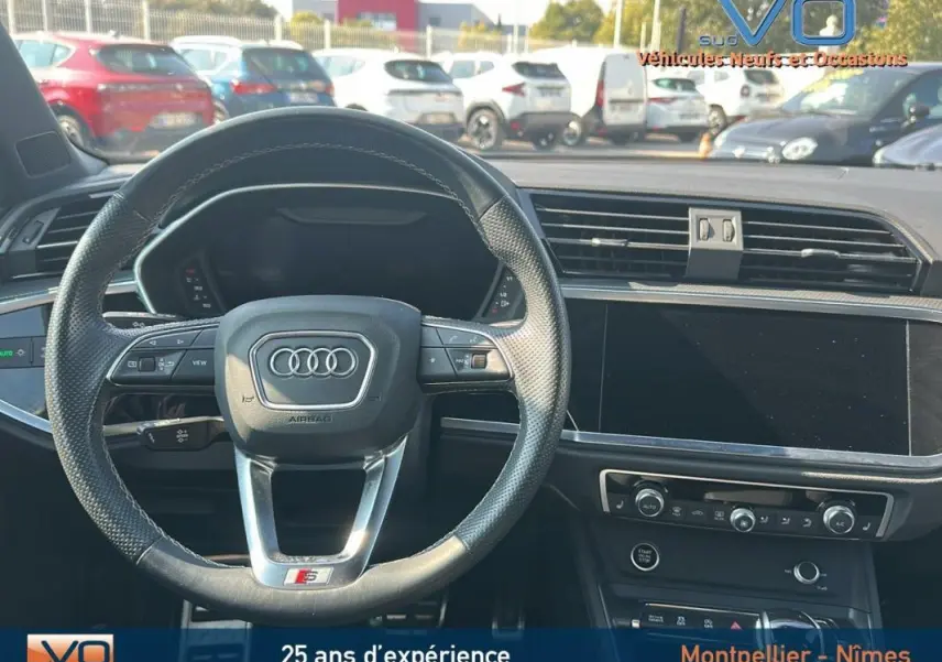 Vue intérieure centrée sur le volant noir perforé S line et le tableau de bord moderne de l'Audi Q3 Sportback 2020.