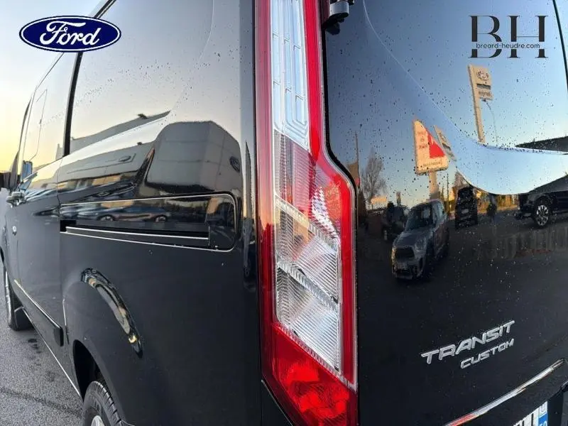 Vue arrière côté droit du Ford Transit Custom noir Agate métallisé, mettant en valeur le feu arrière et le logo Transit Custom.