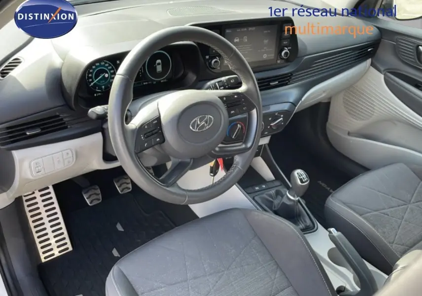 Vue intérieure côté conducteur du Hyundai Bayon blanc polaire 2022, volant cuir multifonction et boîte manuelle visible.