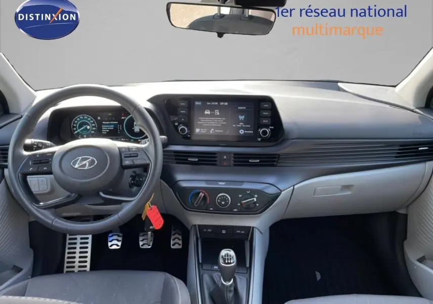 Vue intérieure avant du Hyundai Bayon blanc polaire 2022, avec tableau de bord numérique et volant cuir multifonction.