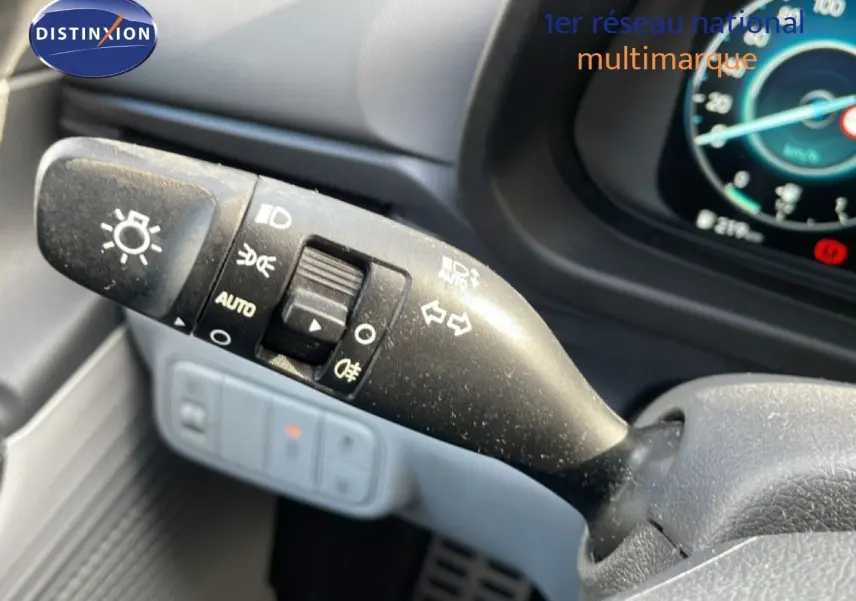 Gros plan sur la commande des feux et clignotants à gauche du volant dans l’habitacle gris noir du Hyundai Bayon blanc polaire.