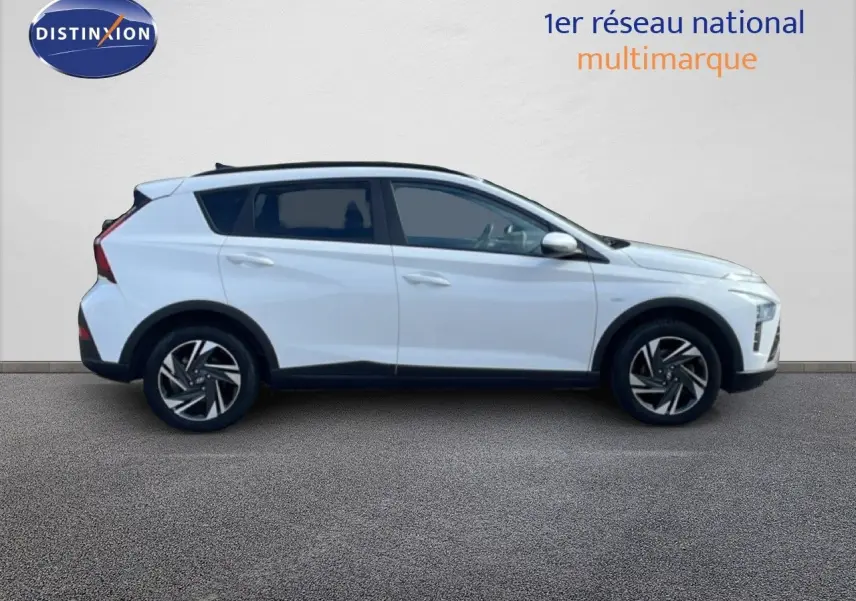 Profil droit du Hyundai Bayon blanc polaire 2022, version hybride avec jantes alliage et toit noir contrasté.