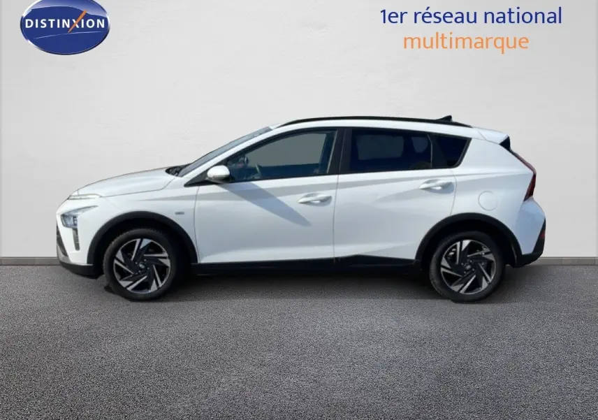 Vue de profil côté gauche d'un Hyundai Bayon blanc polaire avec jantes alliage noires et toit noir.