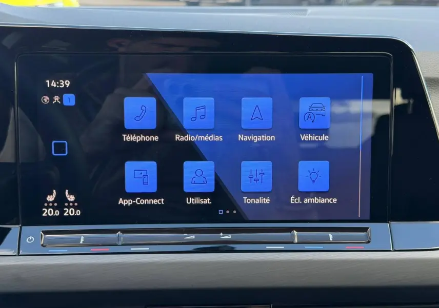 Écran tactile central de la Volkswagen Golf 2024 affichant les options de navigation et radio, avec commandes climatisation en dessous.