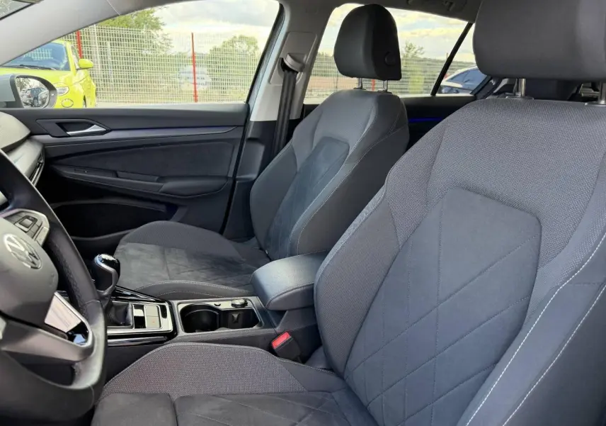 Vue intérieure côté avant droit de la Volkswagen Golf 1.5 TSI Style 2024 avec sièges sport gris et accoudoir central.