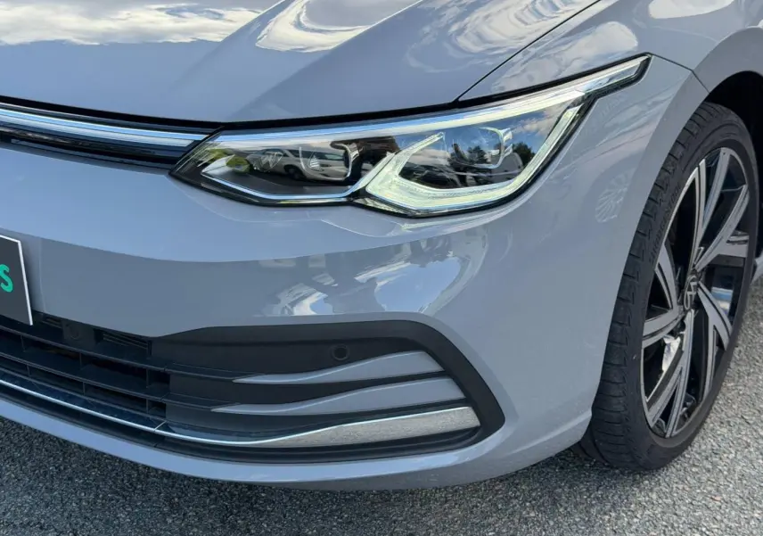 Gros plan sur l'avant droit gris lunaire de la Volkswagen Golf 2024, mettant en valeur le phare LED et la jante alu.