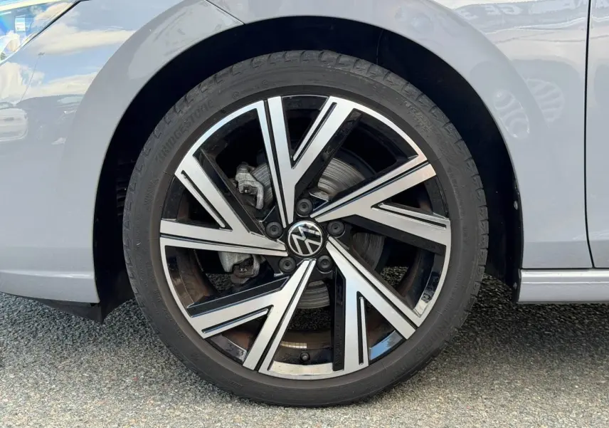 Gros plan sur la roue avant gauche de la Volkswagen Golf 1.5 TSI gris lunaire avec jante alliage noire et argent.