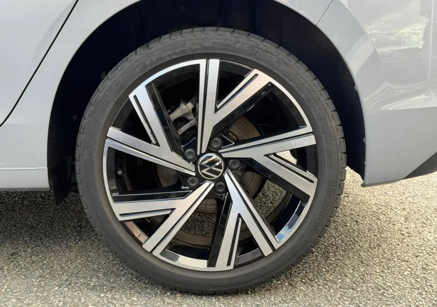 Gros plan sur la roue arrière droite de la Volkswagen Golf 2024 gris lunaire avec jante alliage noir et argentée.