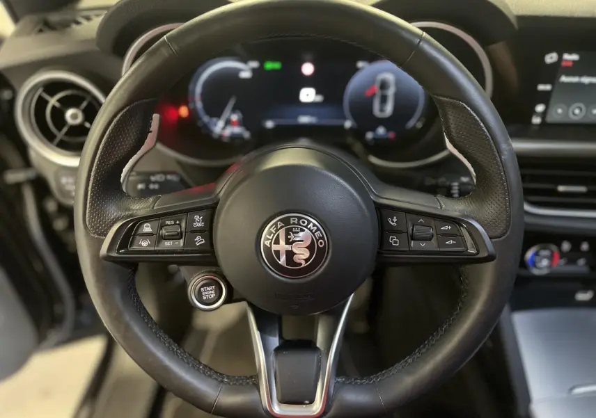 Gros plan sur le volant sport en cuir noir de l'Alfa Romeo Stelvio 2024 avec tableau de bord digital lumineux.