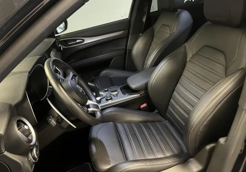 Intérieur noir de l'Alfa Romeo Stelvio Veloce 2024, vue côté conducteur avec sièges sport en cuir et console centrale.