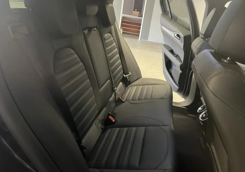 Vue intérieure côté droit des sièges arrière en cuir noir de l'Alfa Romeo Stelvio 2024 avec porte ouverte.