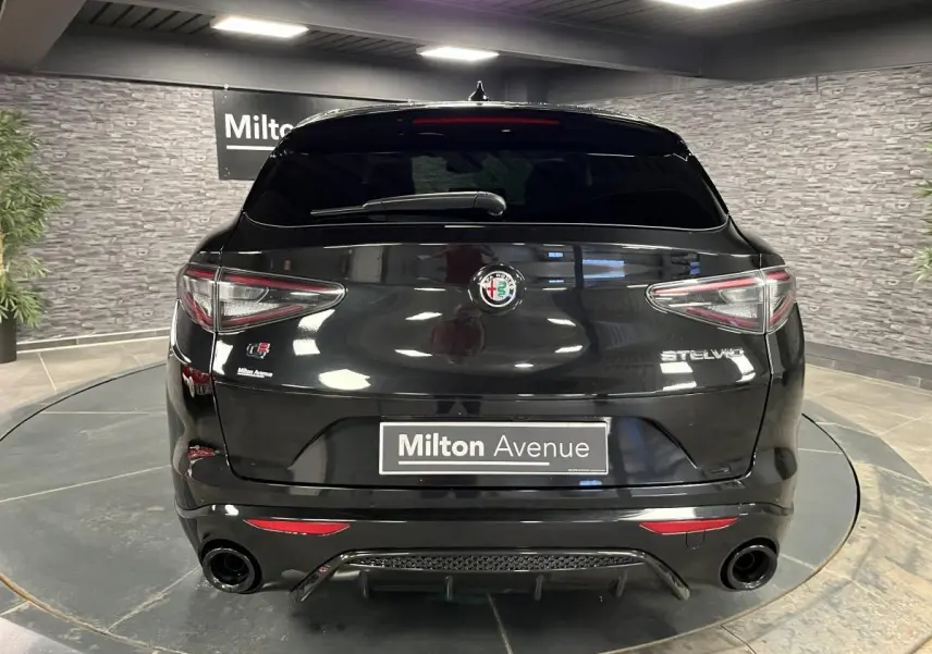 Vue arrière d'un Alfa Romeo Stelvio noir Vulcano avec double sortie d'échappement et badge Veloce visible.