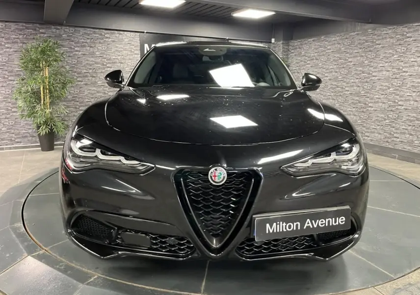Vue frontale d'un Alfa Romeo Stelvio Veloce noir métallisé avec calandre en V noir et phares LED distinctifs.