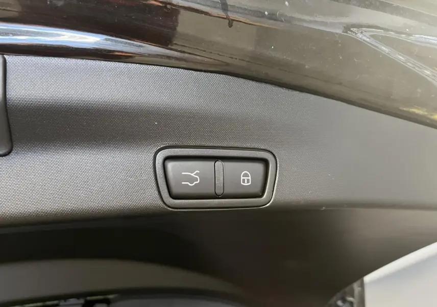 Gros plan sur les boutons d'ouverture et de verrouillage du hayon électrique noir d'un Alfa Romeo Stelvio 2024 noir Vulcano.