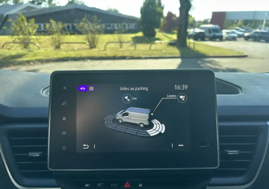 Vue intérieure côté conducteur du Renault Trafic Fourgon gris urbain 2025, avec sièges tissu et volant multifonction.