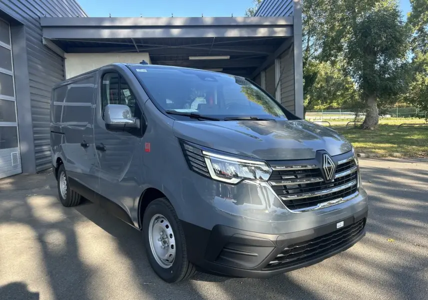 Vue latérale droite d'un Renault Trafic Fourgon gris urbain 2025, avec roues acier et silhouette épurée en showroom.
