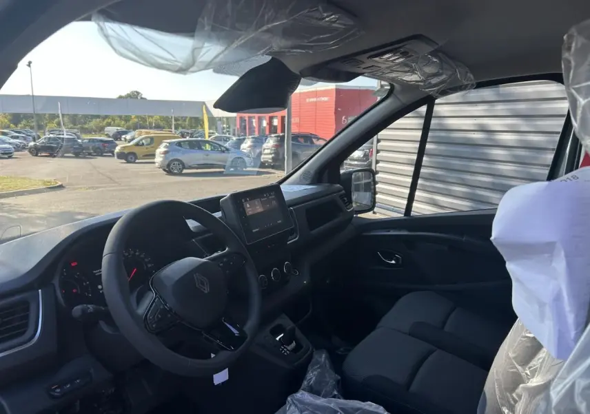 Vue 3/4 arrière droite du Renault Trafic Fourgon gris urbain 2025, avec portes arrière fermées et jantes acier.