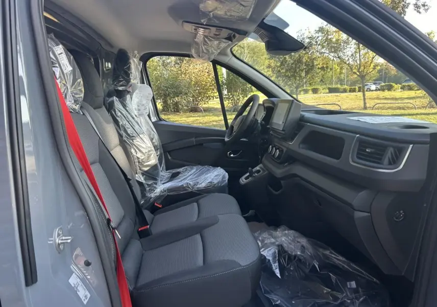 Vue latérale droite du Renault Trafic Fourgon gris urbain 2025, avec roues acier et porte coulissante visible.