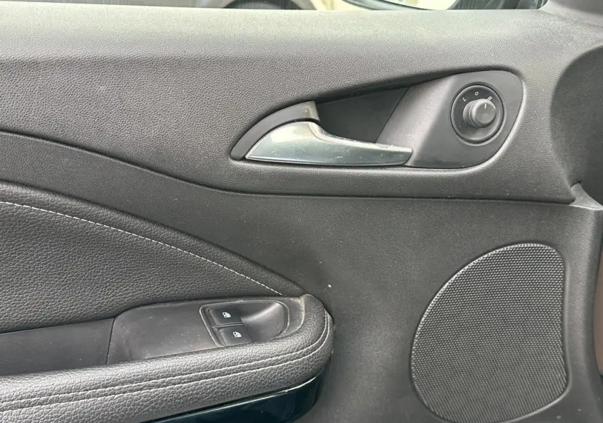 Gros plan sur la poignée intérieure et les commandes de la porte avant gauche de l’Opel Adam marron de 2016.