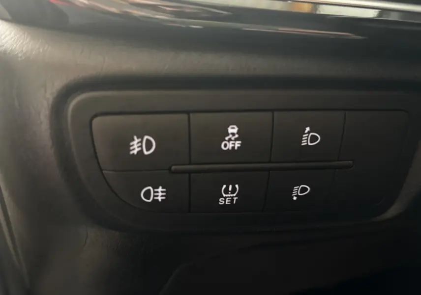 Gros plan sur les commandes d'éclairage et d'assistance du tableau de bord d'une Fiat Tipo blanche de 2021.