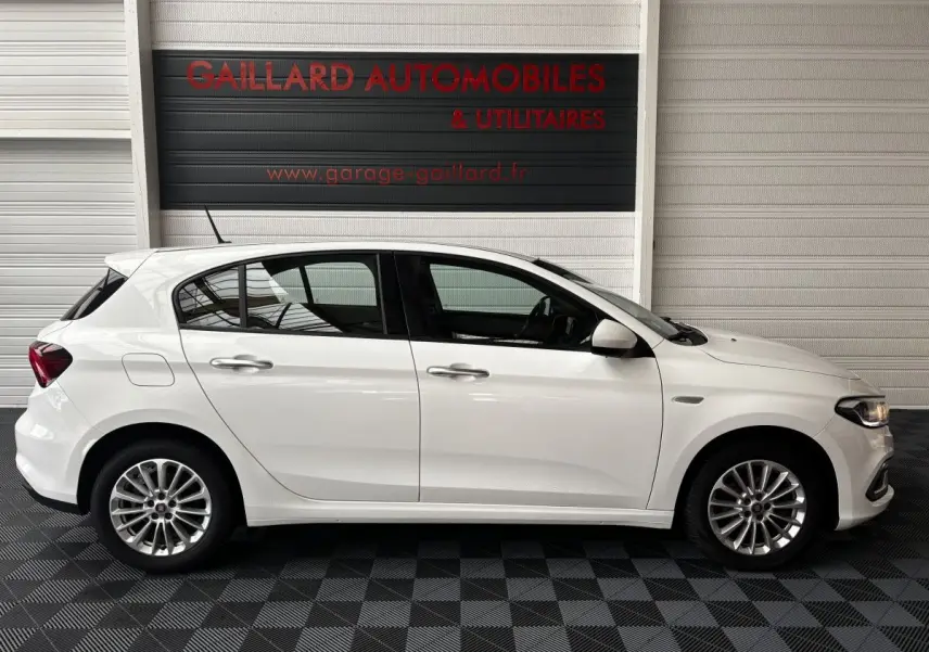 Profil côté droit d'une FIAT TIPO blanche 2021 en intérieur, avec jantes alliage et poignées de porte chromées.