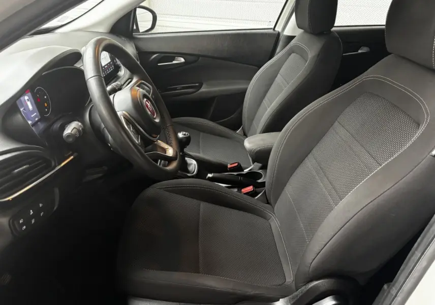 Intérieur avant droit du Fiat Tipo 1.6 MultiJet 2021, sièges noirs, volant cuir multifonctions et levier de vitesses manuel.