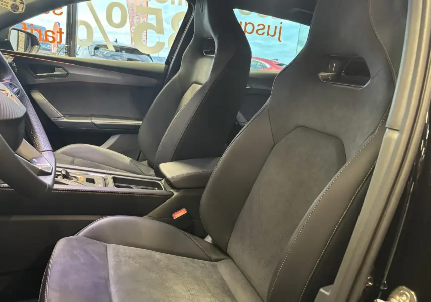 Vue intérieure côté droit des sièges baquets suédine noir et cuir du CUPRA Leon 2026 avec surpiqûres cuivrées et console centrale.