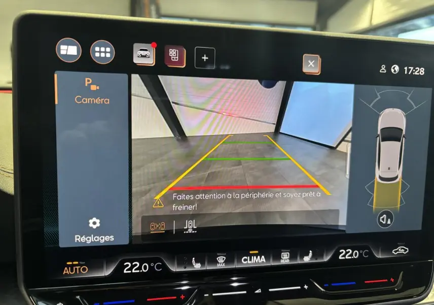 Écran tactile intérieur affichant la caméra de recul et l’aide au stationnement du CUPRA Leon noir midnight, vue de face.