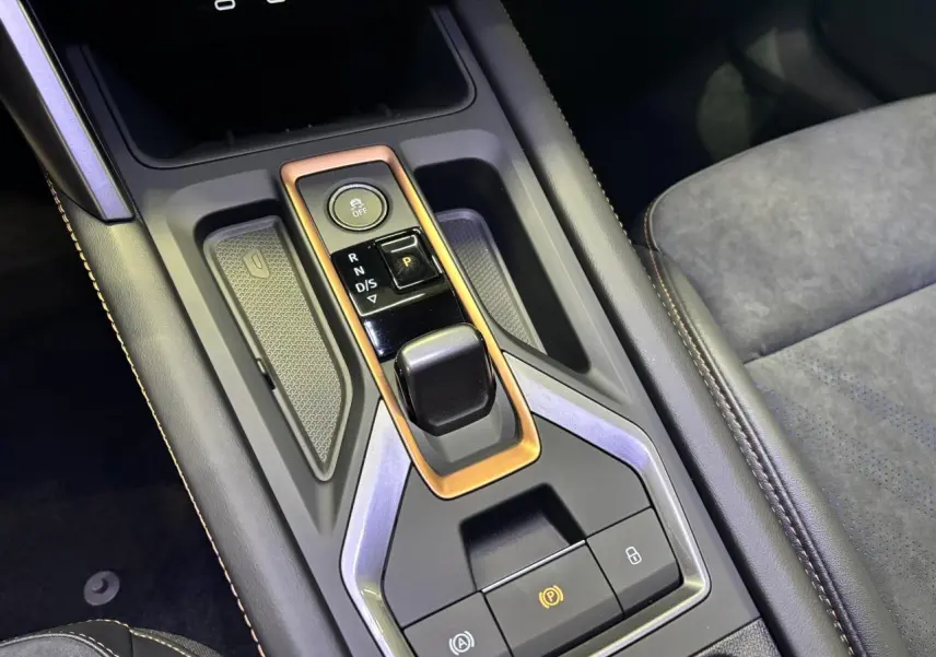 Vue rapprochée de la console centrale noire avec surpiqûres cuivrées et levier de vitesses automatique sur CUPRA Leon noir midnight.