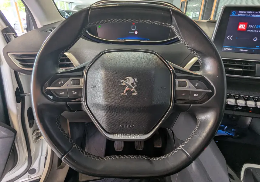 Vue rapprochée du volant cuir noir du Peugeot 3008 HDi 130 Allure 2018, avec tableau de bord digital et écran central visible.