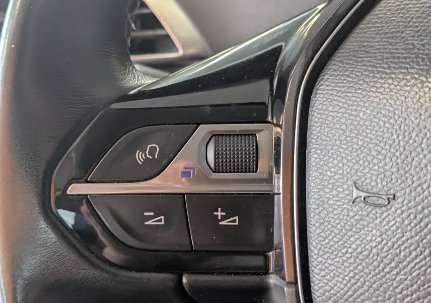 Gros plan sur les commandes de volume et téléphone au volant en cuir noir du Peugeot 3008 blanc toit noir 2018.