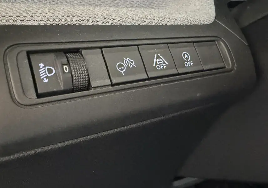 Gros plan sur les commandes de réglage des phares et d’aide à la conduite dans l’habitacle noir du Citroën C3 Turbo 100 BVM6.