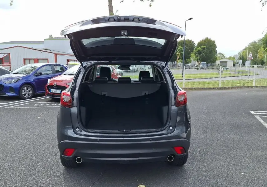 Vue arrière d'un Mazda CX-5 gris 2015 avec coffre ouvert, révélant un espace de chargement spacieux.