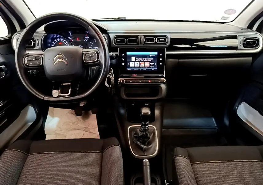 Vue intérieure avant du tableau de bord et volant cuir noir d'une Citroën C3 blanche avec écran tactile central.