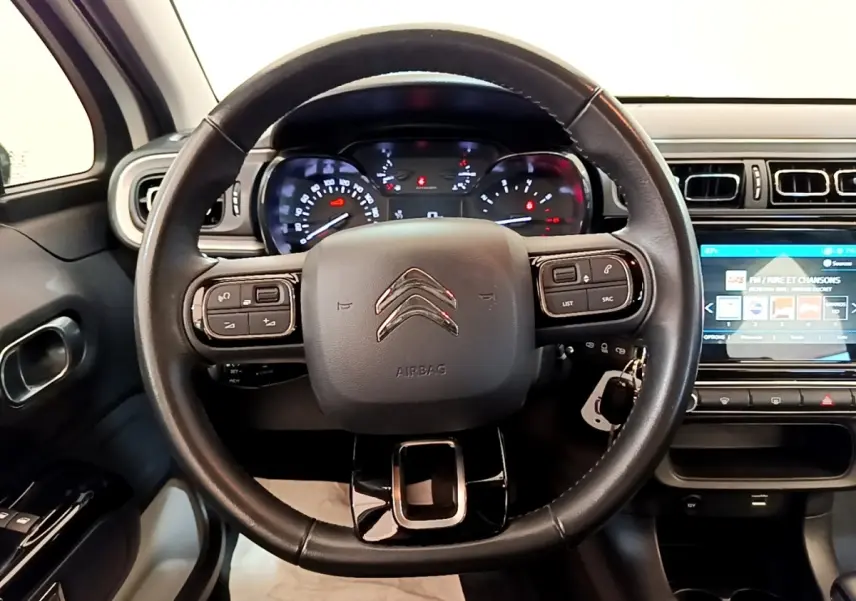 Vue rapprochée du volant cuir noir de la Citroën C3 2021 avec tableau de bord et écran tactile visible à droite.