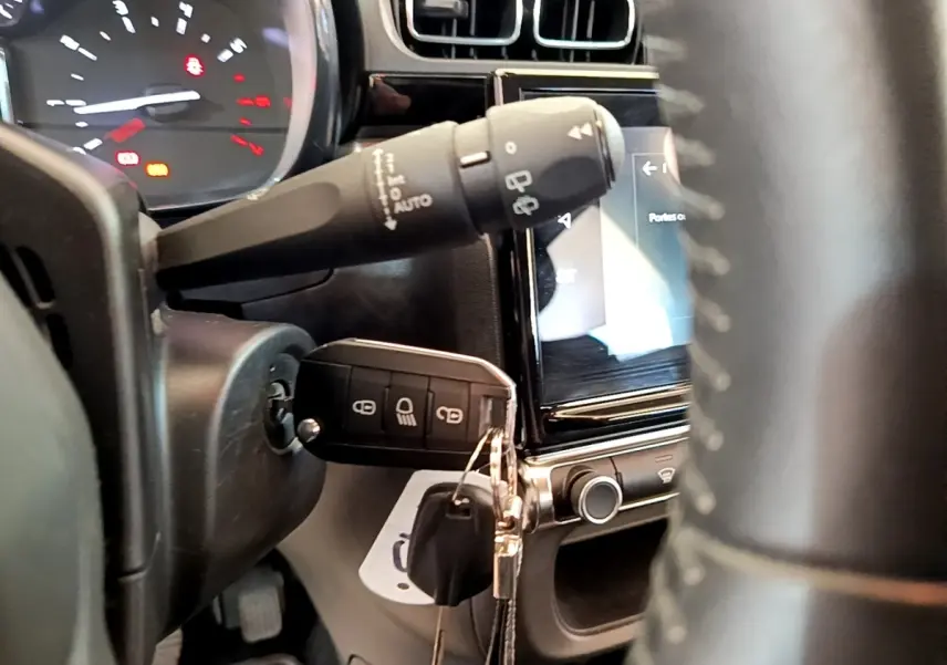 Gros plan intérieur sur le volant et la clé insérée du Citroën C3 blanc, avec tableau de bord et écran tactile visibles.